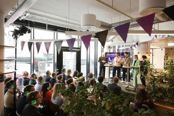 Panel talk in a bright room with bunting and an audience wearing headphones