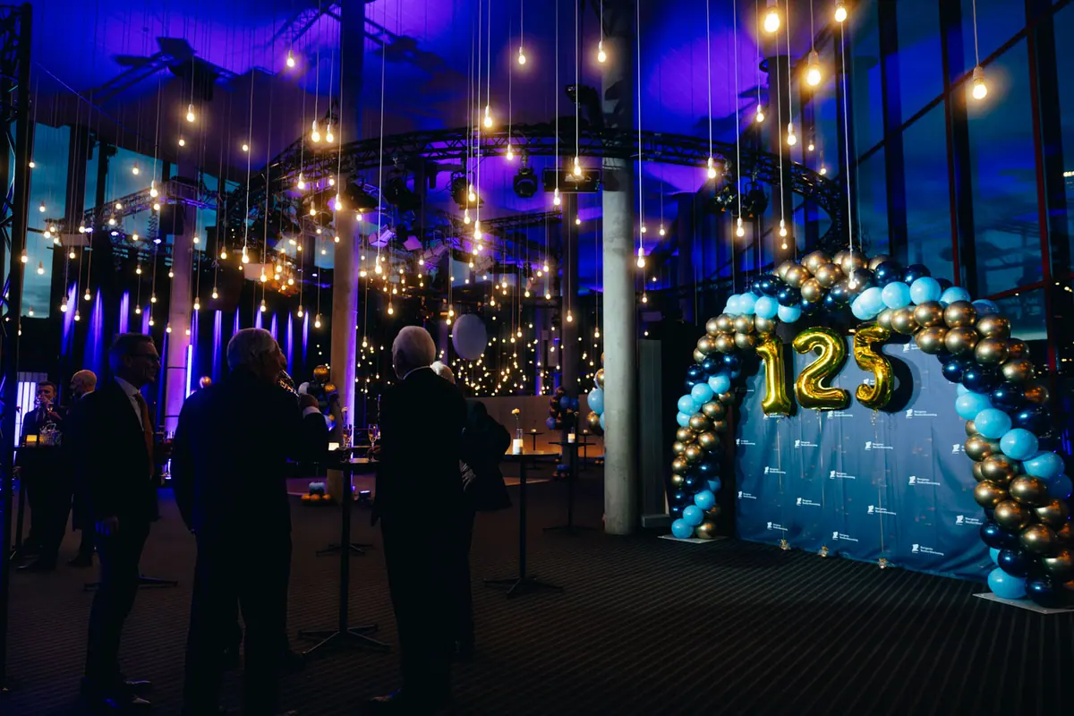 Party venue with string lights and a balloon arch with the number 125