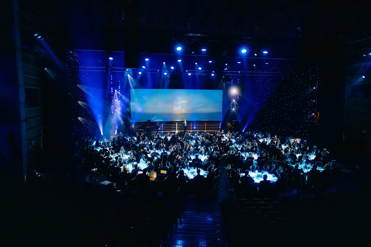 Gala dinner with round tables in blue light by the stage at the Bergen Shipowners' Association anniversary