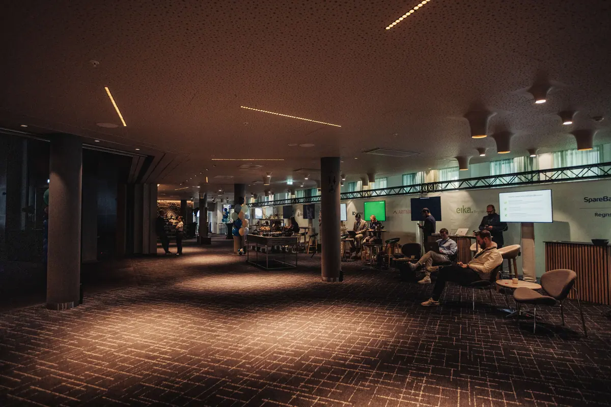 Dimly lit expo area with lounge seating and screens
