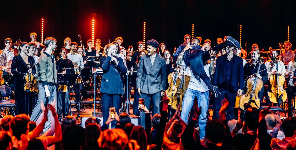 Artists and youth orchestra receiving applause on stage at Red Bull Symphonic