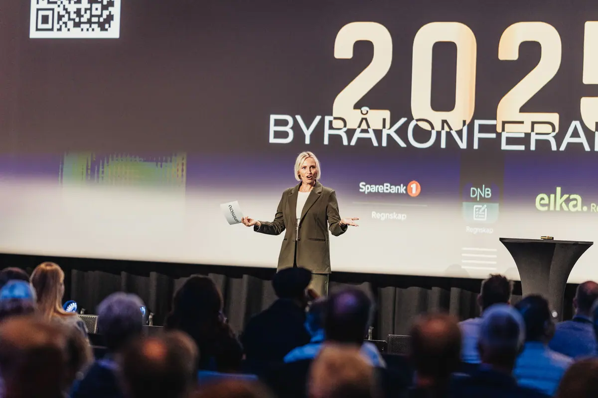 Speaker on stage before a screen showing «Byråkonferansen 2025» and partner logos