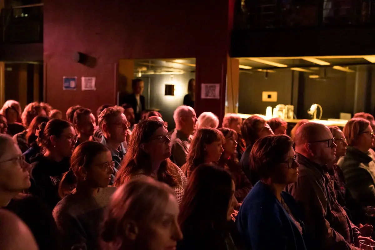 Audience in red light in the hall at Kvarteret during the Aarebrot Lecture