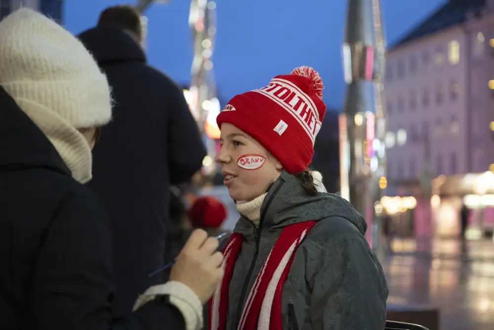 Young Brann supporter in a hat and face paint being interviewed on Torgallmenningen
