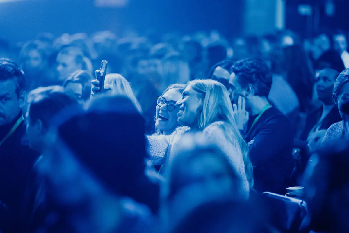 Laughing audience in blue light at Volum