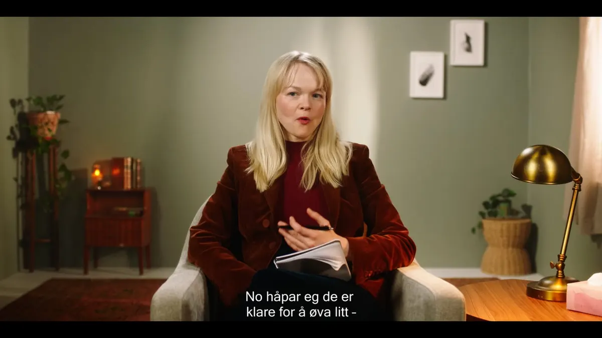 Woman in a red velvet blazer speaking from an armchair in a living room, scene from Parterapi