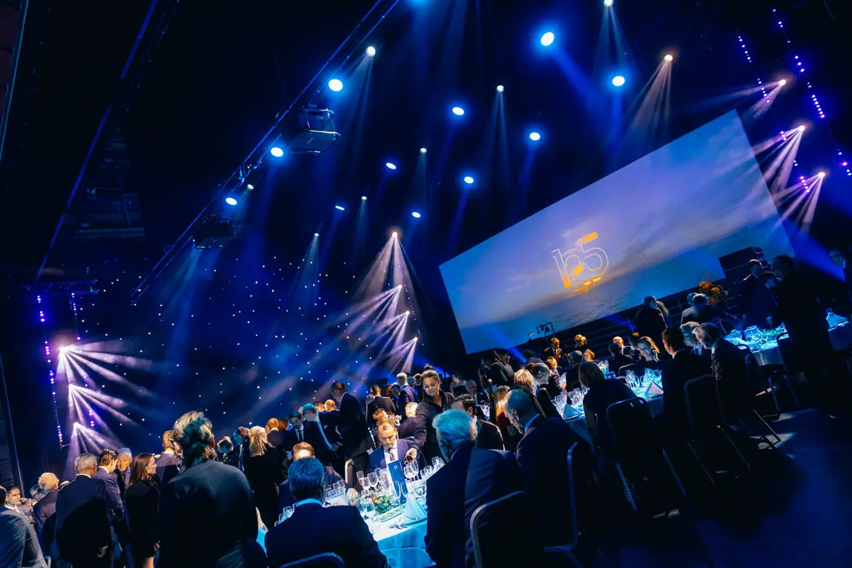 Gala dinner in blue light with the 125 logo projected on a large screen