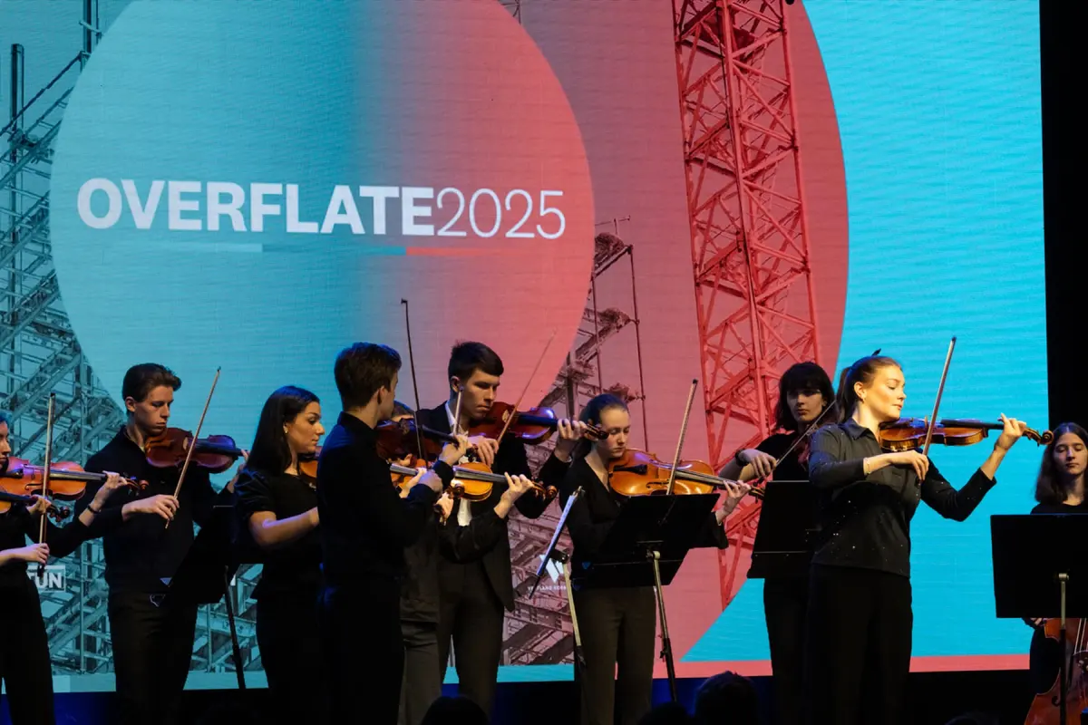Young string players performing on stage in front of a screen reading «Overflate 2025»