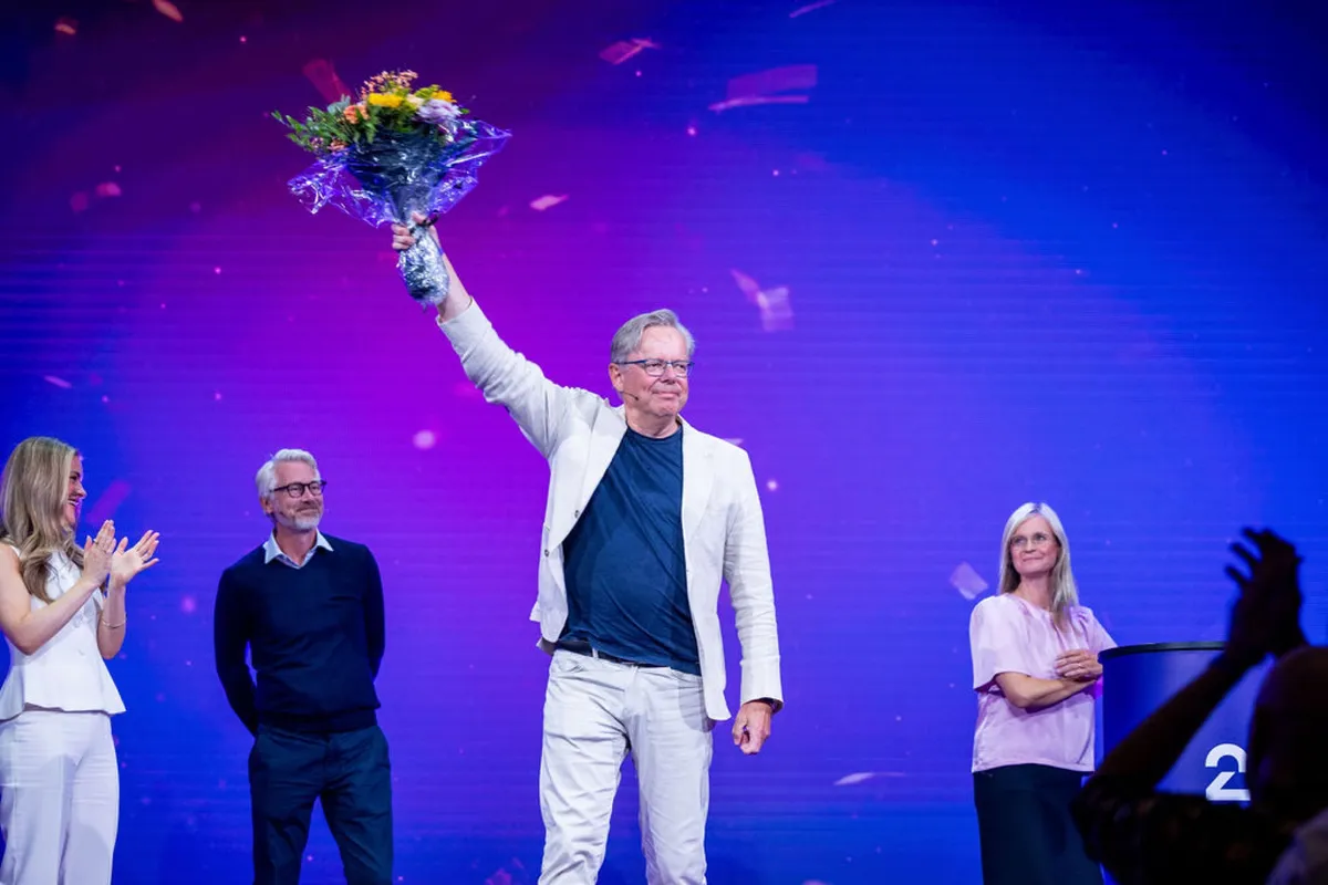 An honoree raising a bouquet of flowers on stage