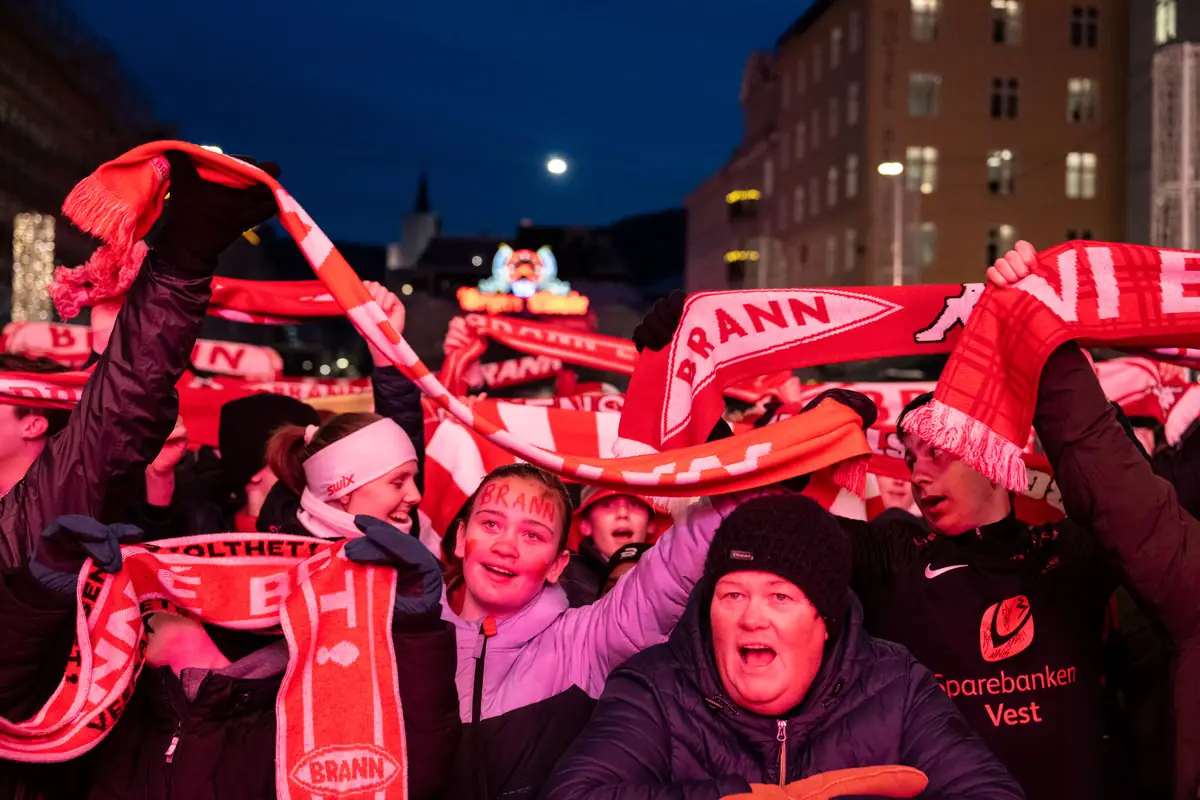 Brann supporters raising red and white scarves on Torgallmenningen in the evening
