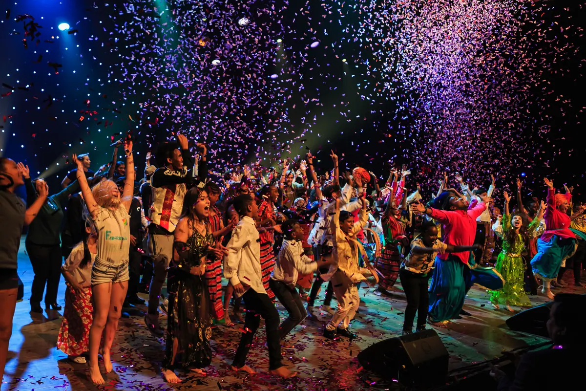 Children and young people dancing in a confetti shower on stage at the Rafto Foundation's 30th anniversary