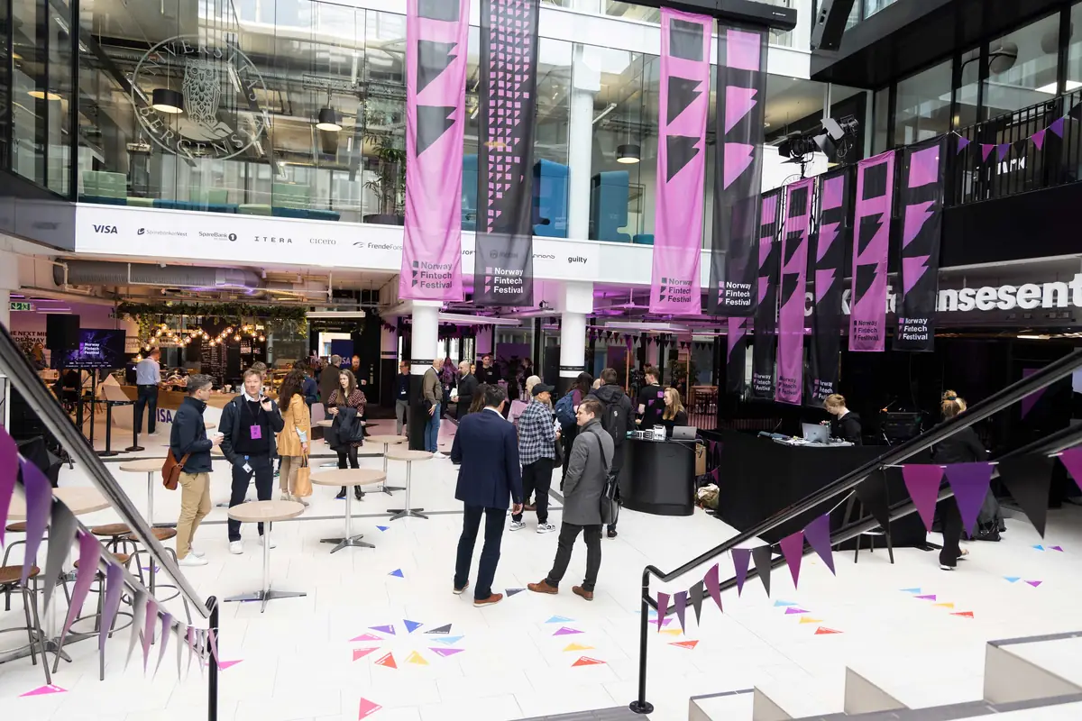Attendees mingling in the Media City Bergen atrium decked with Norway Fintech Festival banners