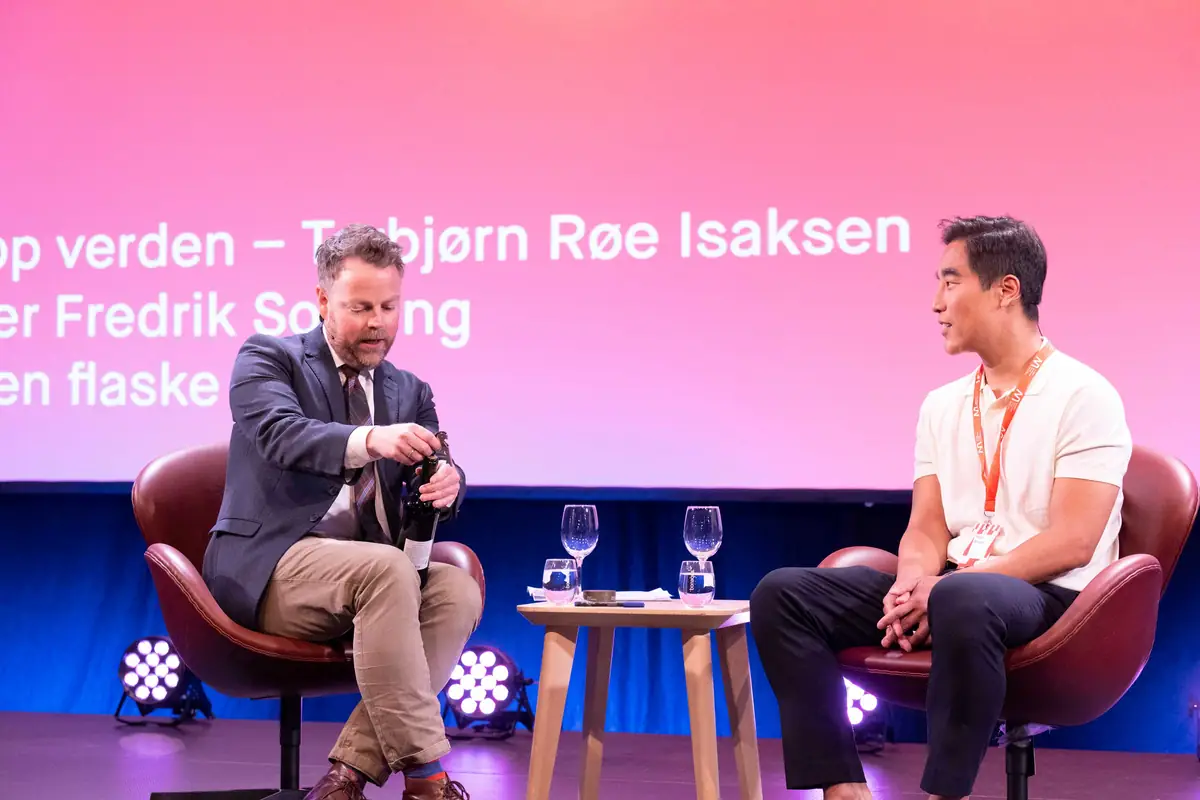 Conversation in armchairs on a pink-lit stage at Nordiske Mediedager