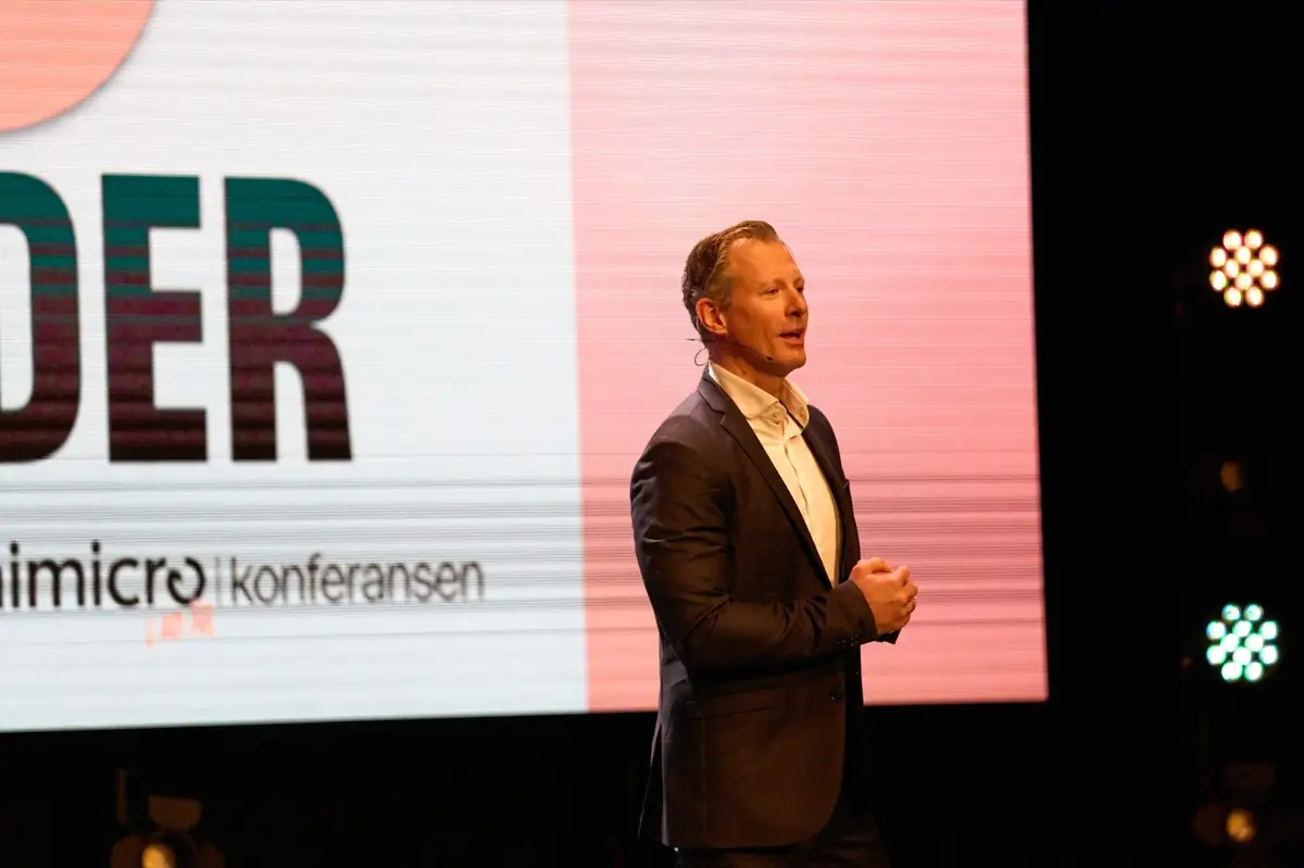 Speaker on stage in front of a large screen at the Unimicro Agency Conference