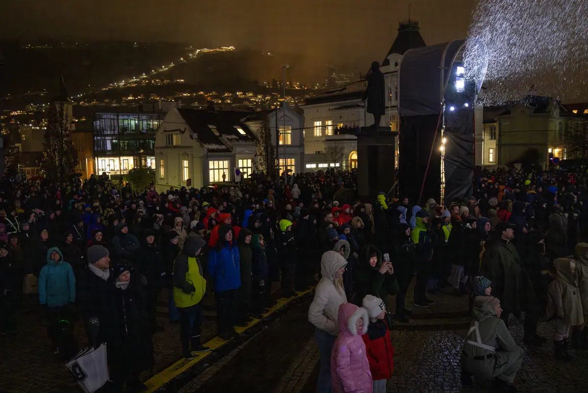 Audience in rain gear gathered at Muséplassen during the light show