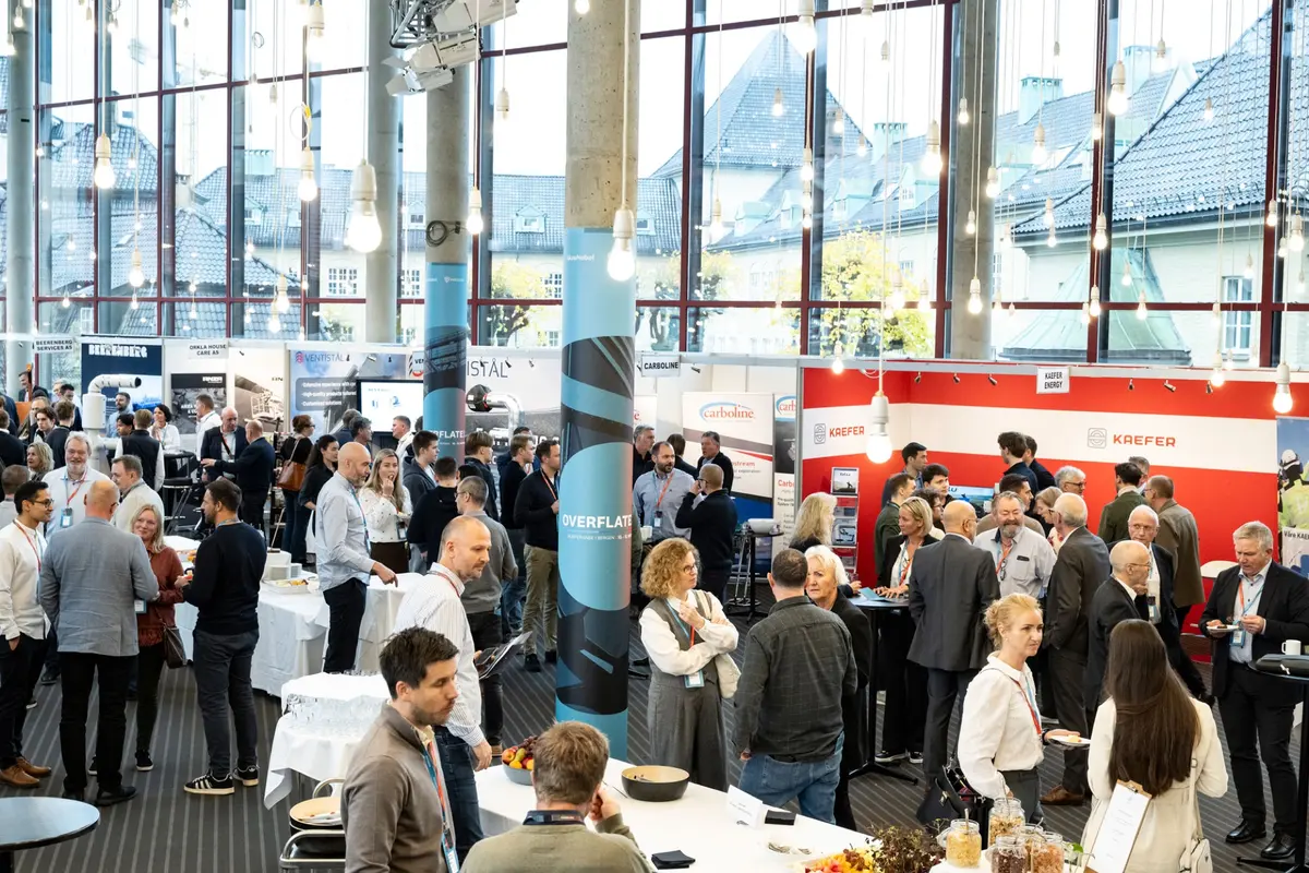 Participants mingling among exhibition stands in the Grieghallen foyer