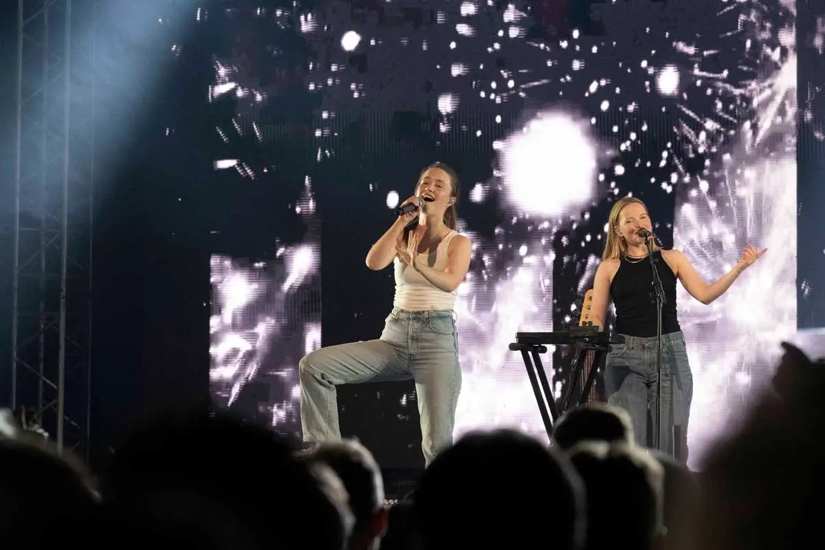 Two female singers on stage before a sparkling LED wall at TV 2's 30th anniversary