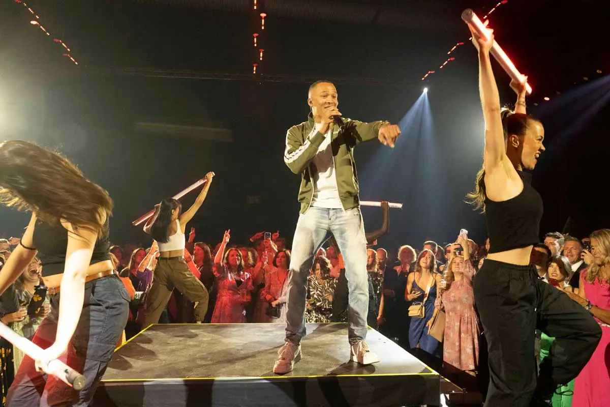 Artist on stage with dancers holding light sticks at TV 2's 30th anniversary