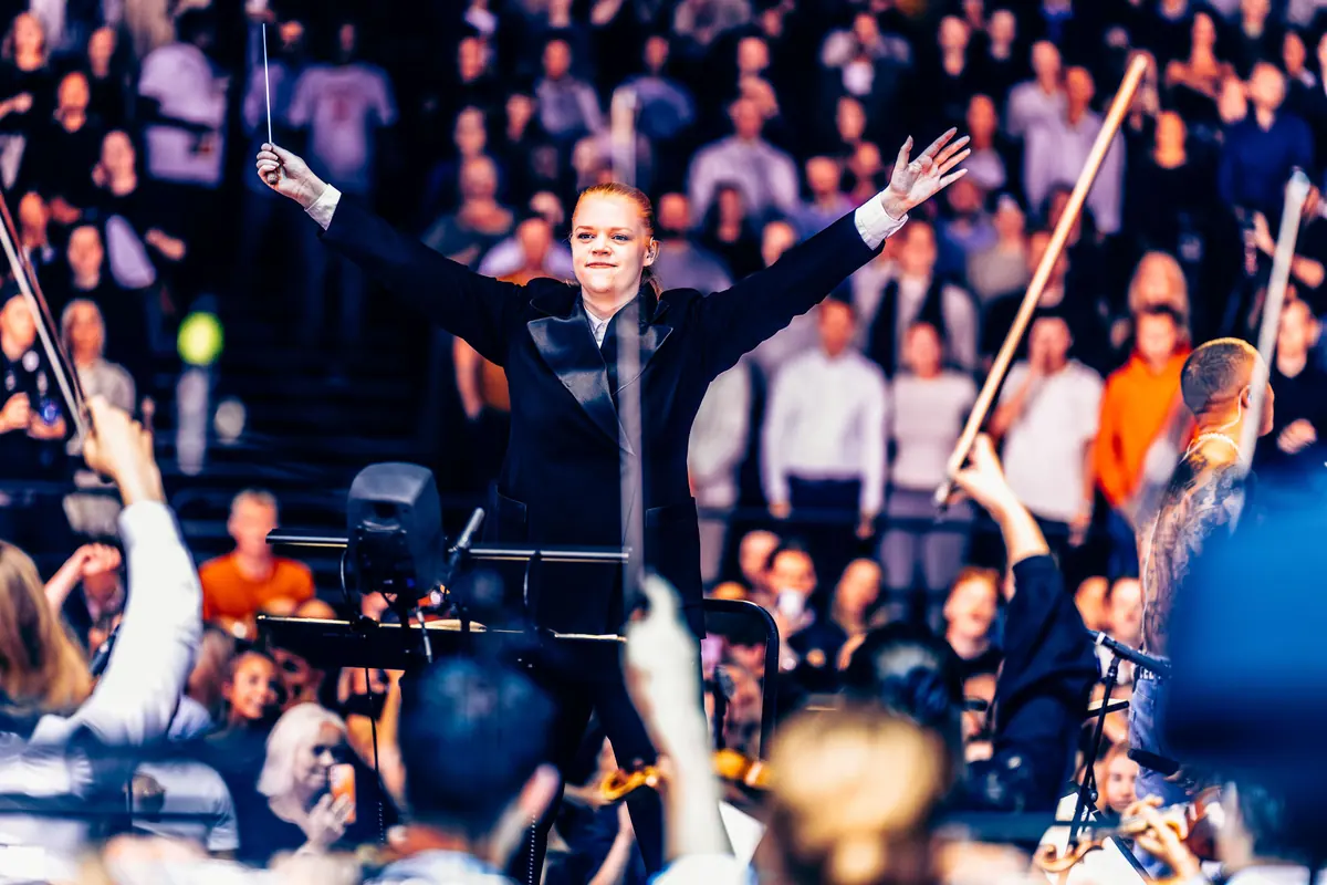 Conductor with arms raised before the orchestra and audience at Red Bull Symphonic