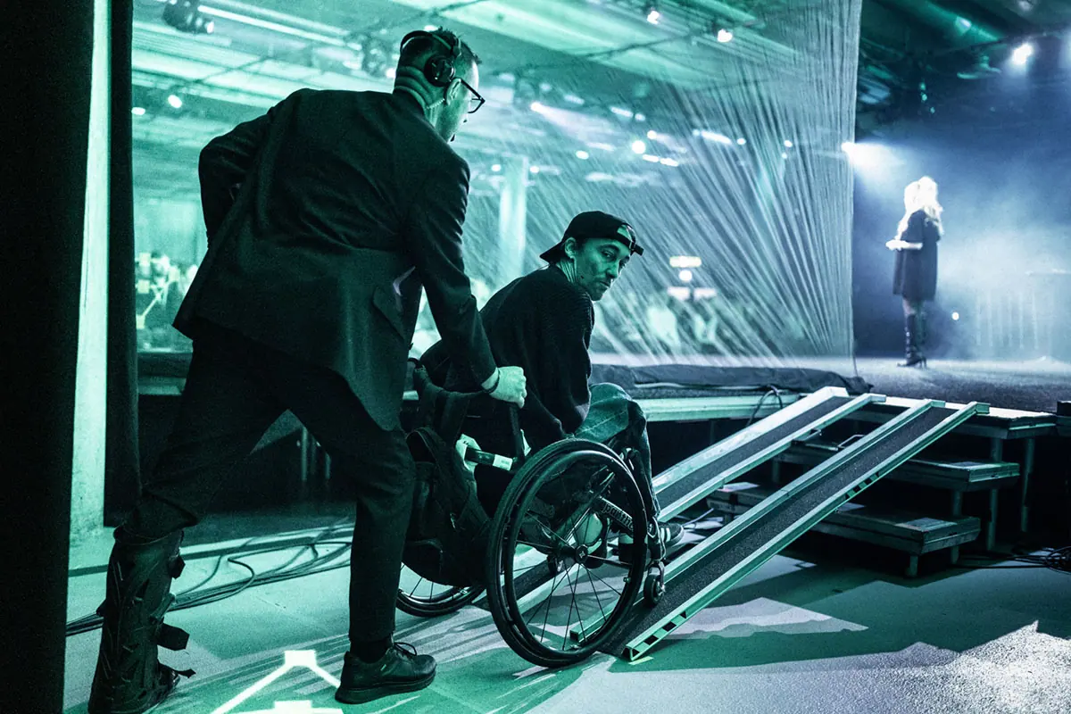 Stagehand helping a wheelchair user up the ramp to the stage