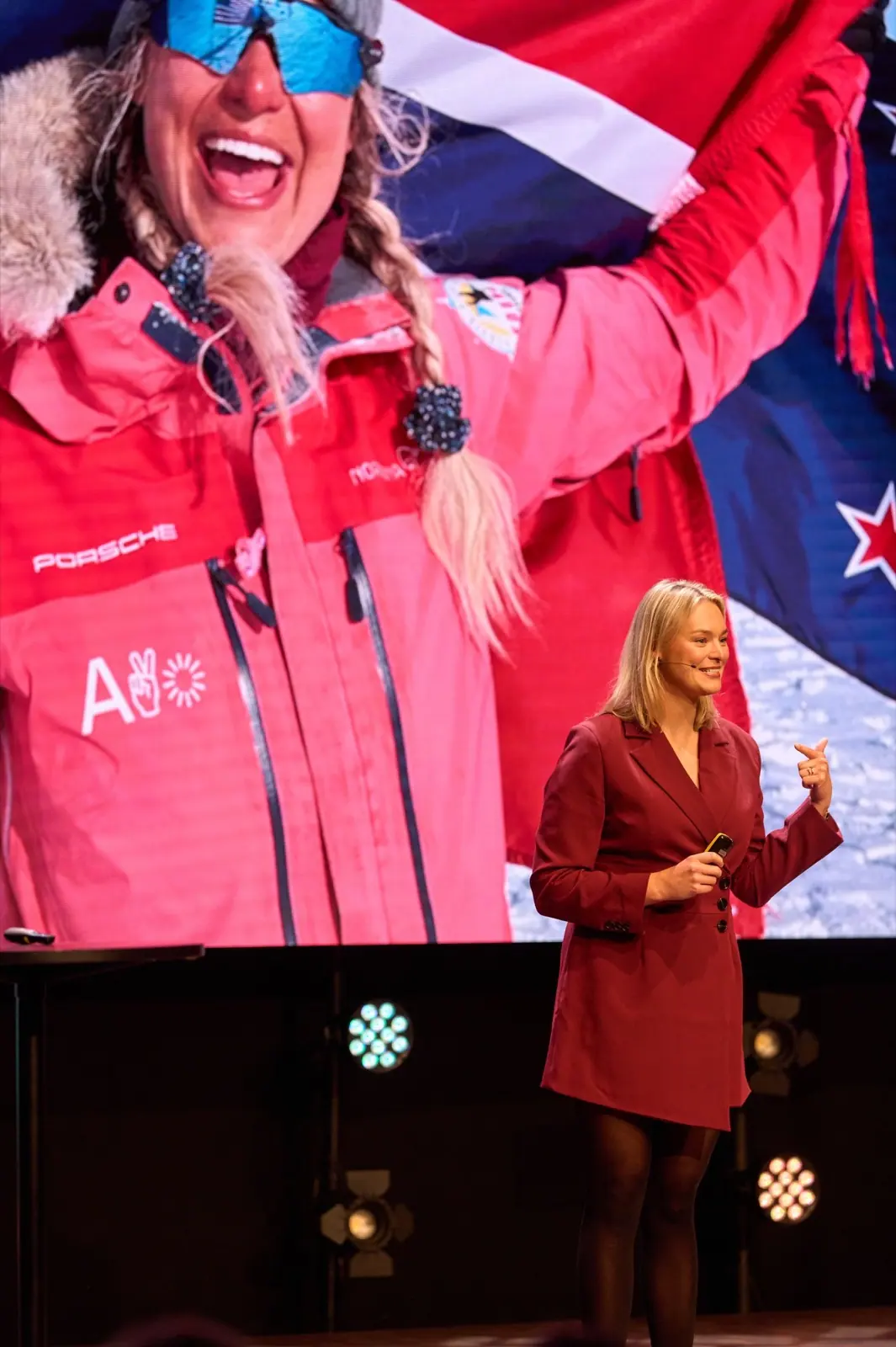 Speaker in a red dress before a large screen showing a polar explorer