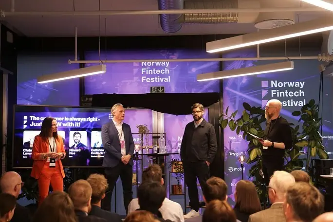 Four people on a small stage in front of Norway Fintech Festival screens