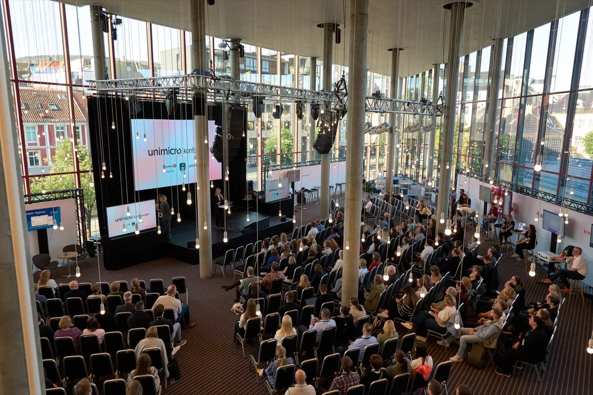 Overview of the glass-walled conference hall and audience at the Unimicro Agency Conference