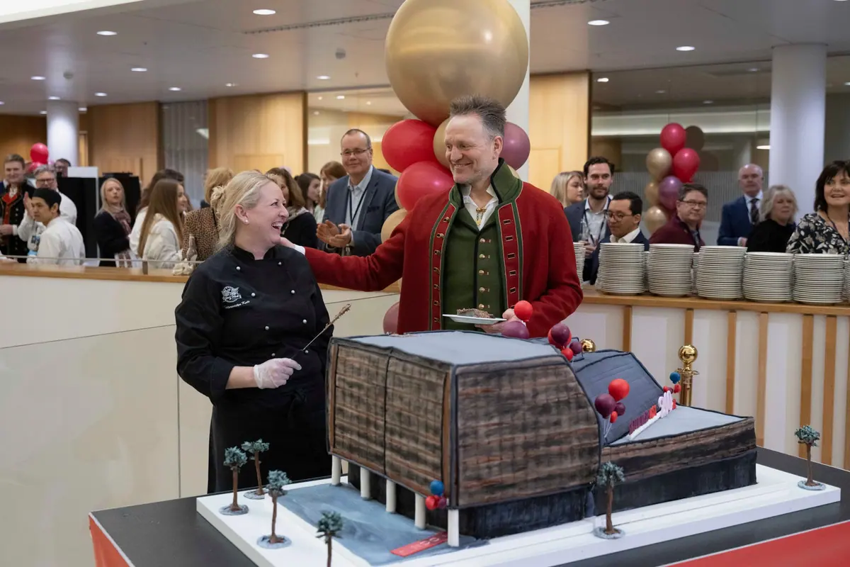 Cake-cutting with a building-shaped cake at a Sparebanken Norge celebration