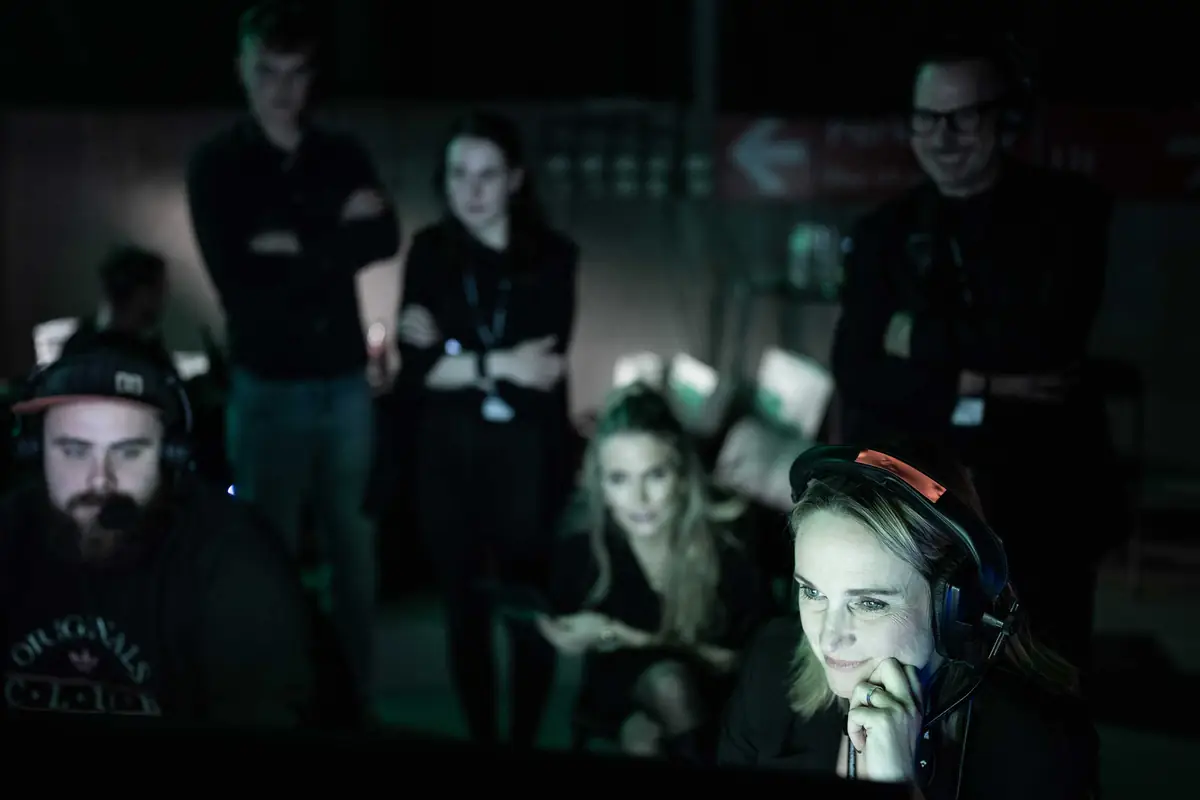 Production team with headsets following screens in the dark behind the stage
