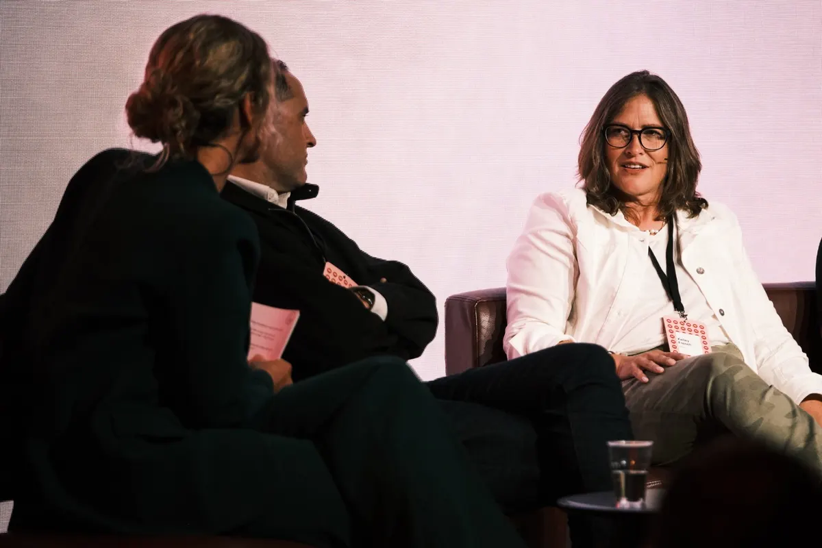 Three people in conversation on sofas on stage