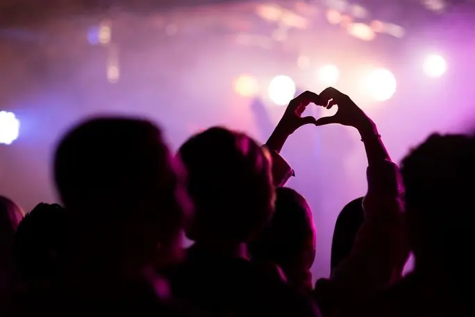 Silhouetted audience making a heart with their hands at a concert